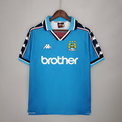Blue manchester city retro jersey with branding on a gray background