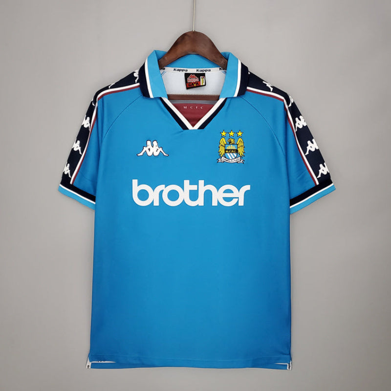 Blue manchester city retro jersey with branding on a gray background