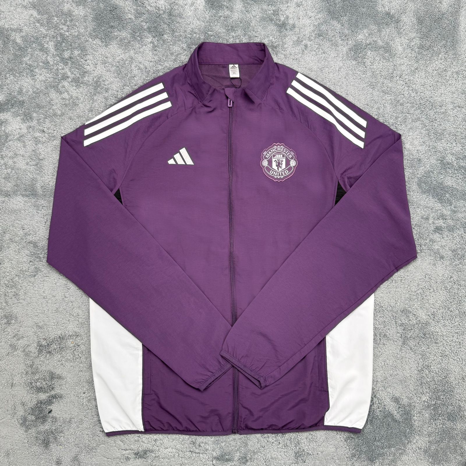 Purple jacket with white stripes and logos on a gray background